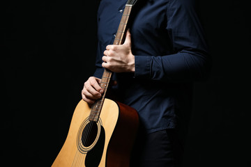 Handsome man with guitar on dark background