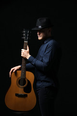 Handsome man with guitar on dark background