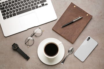 Laptop, cup of coffee, notebook, mobile phone and glasses on table