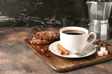 Cup of hot coffee and cookies on table