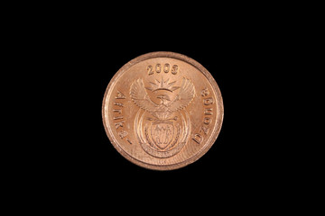 A close up, macro image of a copper colored, South African five cent coin, shot against a black background