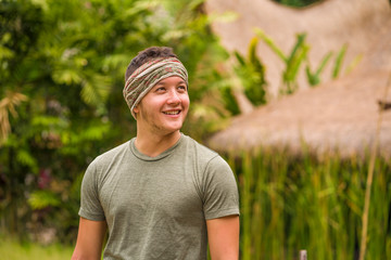 Naklejka na ściany i meble outdoors candid portrait of young attractive and happy hipster man enjoying tropical nature exploring exotic Asian tourist destination during holiday trip smiling cheerful