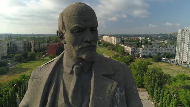 Flight close up face concrete epic monument Lenin Volgograd socialist communist landmark. Typical city Russia central square historical cityscape. Soviet and modern houses. Summer blue sky clouds