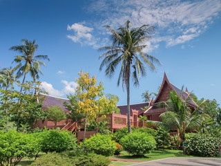 Fototapeta na wymiar View of Thai houses around with green garden and blue sky background, King Rama II Memorial Park, Amphawa District, Samut Songkhram, Thailand.