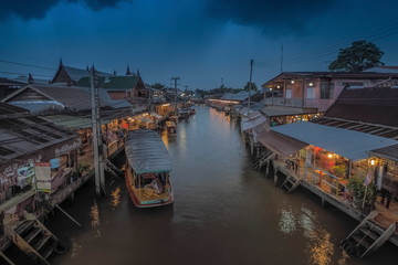 Fototapeta premium view evening above amphawa canal around with wooden Thai houses with rainy sky background, sunset with raining at Amphawa Floating Market, Samut Songkhram, Thailand.