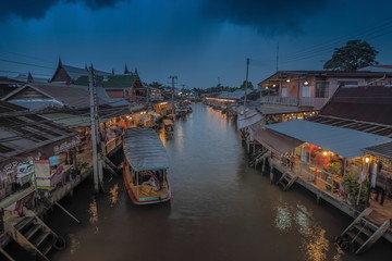 view evening above amphawa canal around with wooden Thai houses with rainy sky background, sunset with raining at Amphawa Floating Market, Samut Songkhram, Thailand.