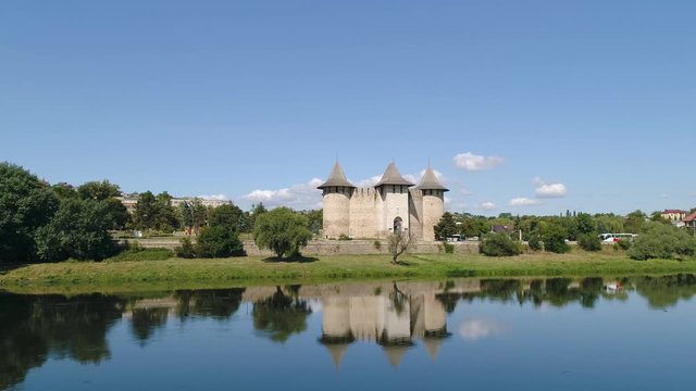 drone aerial shot of soroca fort reflected in water with flying bird over water , view from nistru dnestr river during sunny day