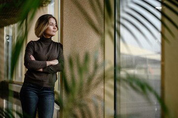 young girl with anticipation looks out the large window of the arrival hall