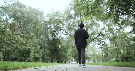 Rear view on man listens to music from cassette player outdoors - Powered by Adobe