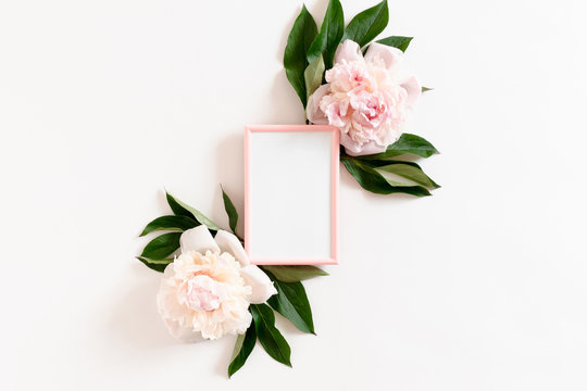 Photo frame mockup with pink peonies and green leaves