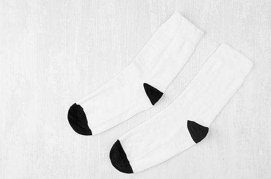 Pair blank white tall socks with black heel flat lay on white wood board, side view - mock up for design, print, presentation, advertising, top view.