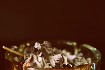 Crumpled piece of paper burns out in a glass ashtray