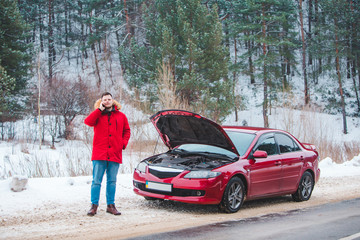 man standing near broken car with opened hood calling help