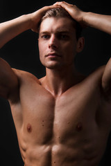 Fototapeta premium Bodybuilder holds muscular arms on head. Photo in studio on a black background.