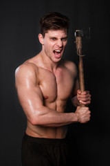 Bodybuilder with an ax in his hands on a black background.