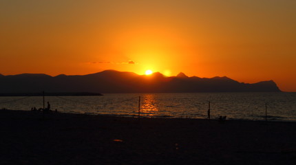 evocative immagine of sunset over the sea with promontory in the background