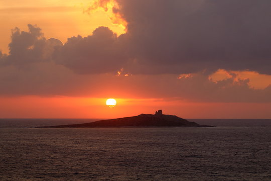 evocative image of sunset over the sea with island in the background