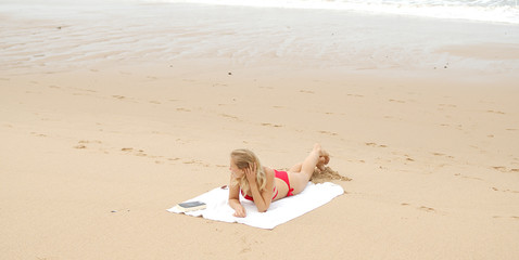 Sexy woman in a bikini relaxes on a sandy beach at the ocean - travel photography