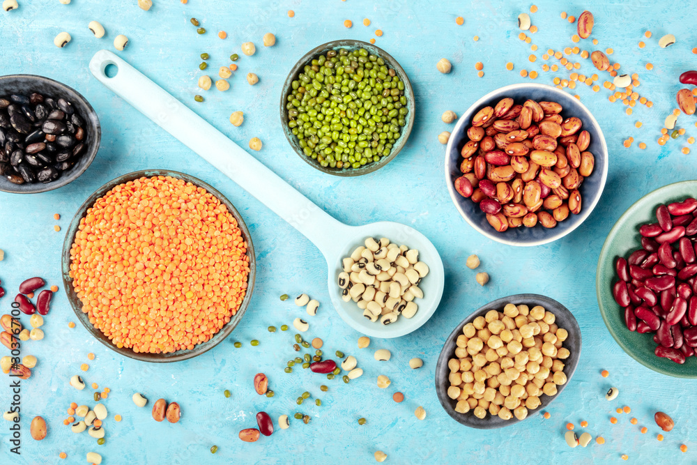 Wall mural legumes, shot from the top on a blue background. vibrant pulses including colorful beans, lentils, c