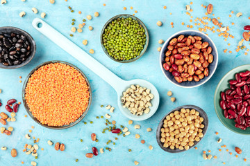 Legumes, shot from the top on a blue background. Vibrant pulses including colorful beans, lentils, chickpeas, a flat lay composition