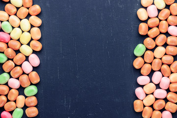 frame of multi-colored candies on a dark background with copy space