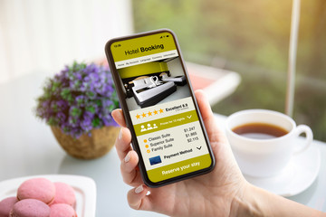 female hands holding phone with app hotel booking on screen