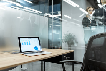 Working place with laptop and some analytic chart on the screen in the office