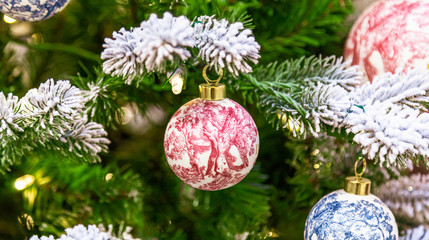 Christmas tree with silver bauble ornaments. Decorated Christmas tree closeup. Balls and illuminated garland with flashlights. New Year baubles macro photo with bokeh. Winter holiday light decoration