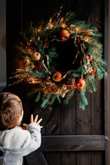 boy and handmade Christmas wreath on a door