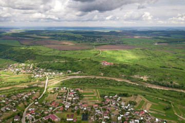 Fototapeta na wymiar Aerial view of town or village with rows of buildings and curvy streets between green fields in summer. Countryside landscape from above.