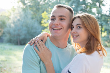 Obraz premium Young teenage couple outdoors. Pretty girl with red hair and handsome boy hugging together.