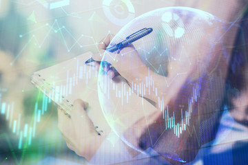 Multi exposure of hands making notes with forex chart huds. Stock market concept.