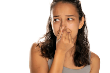 portrait of young woman closing the nose with her fingers on white background