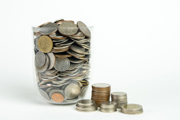 A coin in a glass jar isolated on white background. Saving for the future. Close up shot.