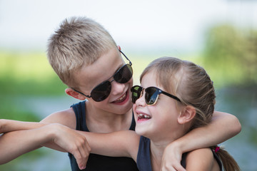 Two children in black sunglasses having fun time outdoors in summer.