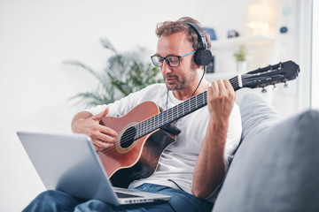 Obraz premium Man playing acoustic guitar in the living room.