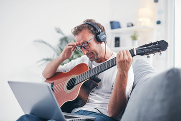 Obraz na płótnie Canvas Man playing acoustic guitar in the living room.