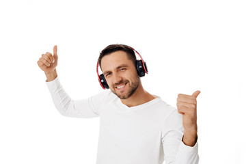 Fototapeta premium happy handsome young man in headphones listening to music and dancing isolated on white background.