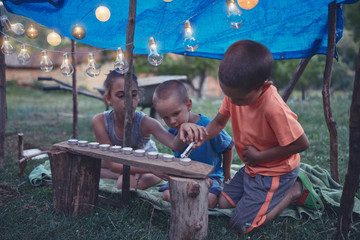 Fototapeta na wymiar Kids making a small tent with candles and lampions in the backyard.