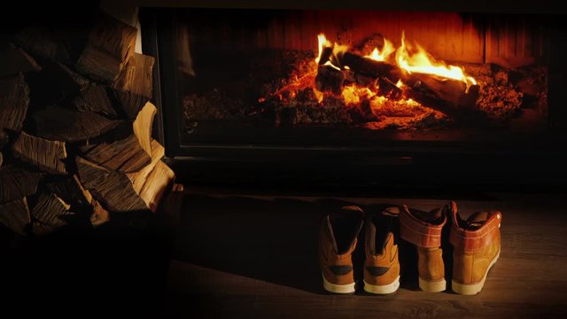 Top view of Men's and women's winter boots dry near the fireplace. Romantic winter evening