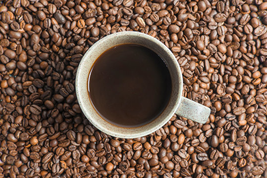 One cup of coffee on the coffee beans background. Flat lay, © stsvirkun