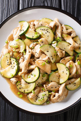 Stir frying of chicken with zucchini close-up on a plate. Vertical top view