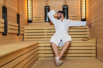Handsome man relaxing in sauna and staying healthy