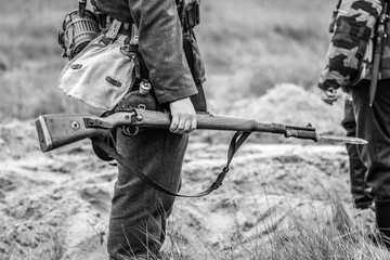 A rifle with a bayonet with a knife in the hands of a Wehrmacht soldier from World War II. Black...