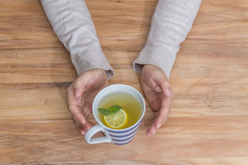 Fototapeta na wymiar Hands holding a healthy hot tea for the flu