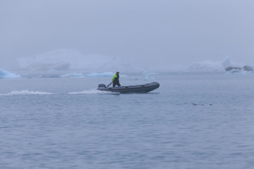 Fototapeta premium Man on a boat between bizarre ice floes of Iceberg lagoon jokulsarlon on the south of Iceland
