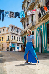 Stylish woman in a blue skirt and white hat on an city street of Cuba