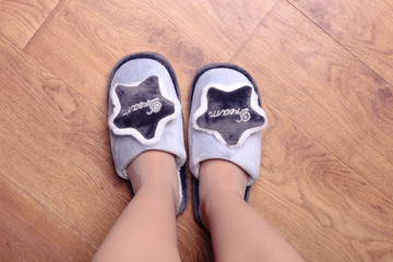Female feet in gray soft slippers