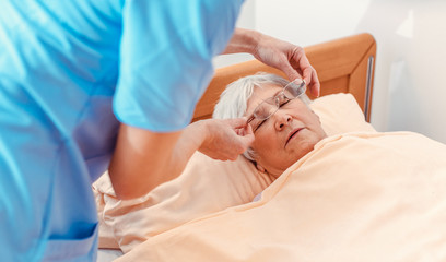 Obraz na płótnie Canvas Nurse taking care of sleeping senior woman in the nursing home