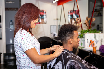 Female hairdresser preparing client for haircut.